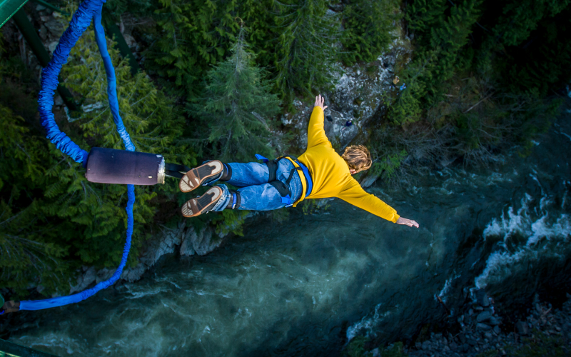 Adventurer bungee jumping from a high platform over the river in Rishikesh