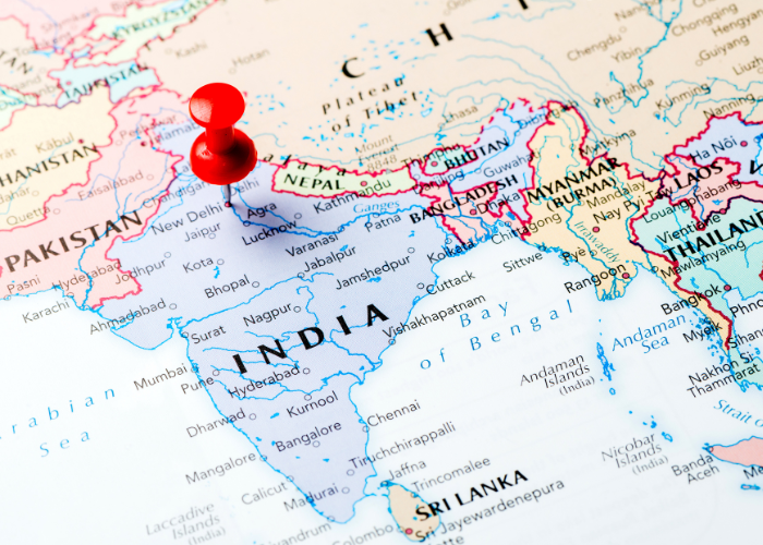 "Flat lay of travel essentials on Indian map including train tickets, journal, and currency notes"