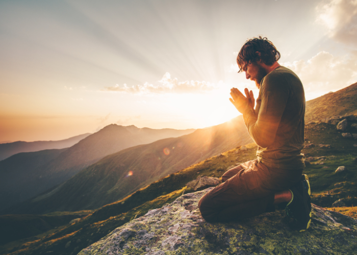"The spiritual side of travel – a man praying during sunrise in the mountains, symbolizing peace, divinity, and the sacred meaning of travel."