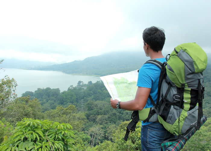 A man standing with a map in hand, representing travel as a journey of learning, exploration, and personal growth.