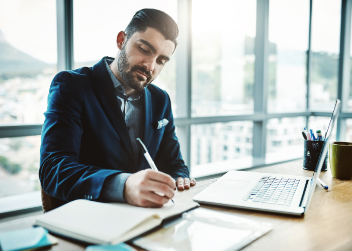A man working at his desk, representing daily work life and the need for travel to break free from monotony.